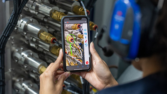 Marine service technician in protective workwear performing maintenance on equipment aboard a vessel, with Alfa Laval service branding visible.
